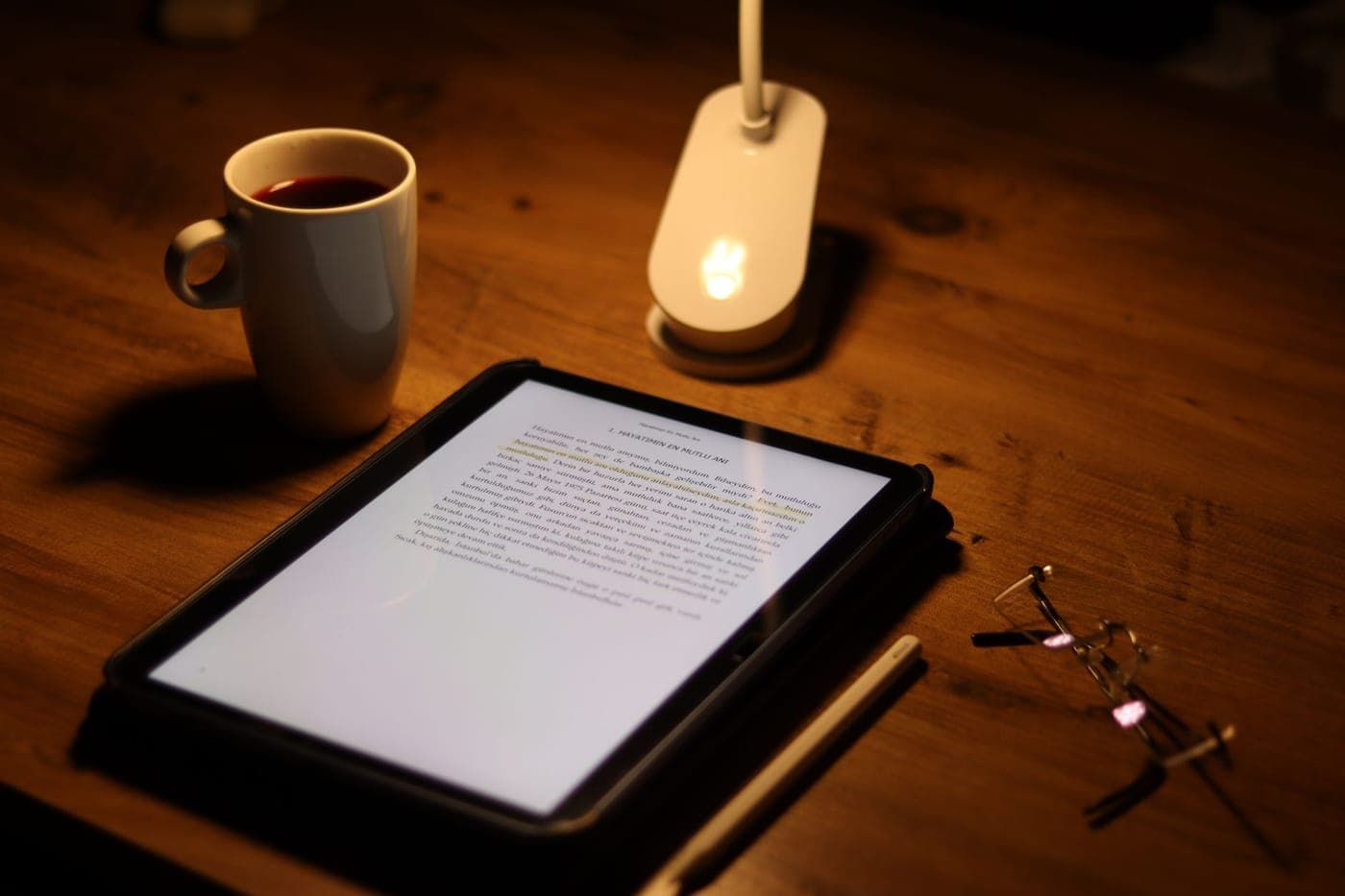 An e-reader and headphones side by side on a desk