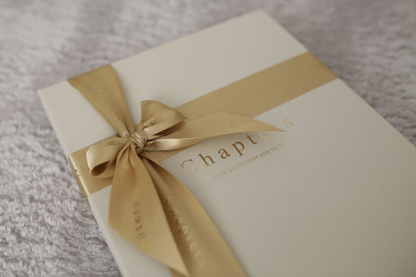 A wrapped gift tied with ribbon beside a stack of books