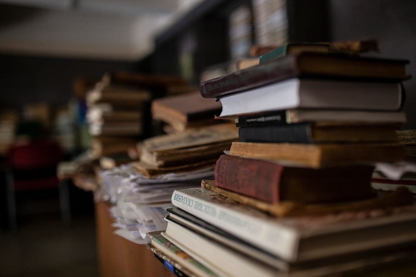 A stack of hardback books on a wooden table